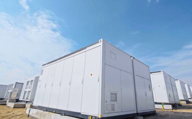 Kontenery bateryjnego magazynu energii BESS zainstalowane na ogrodzonym terenie stacji elektroenergetycznej w otoczeniu lasu.