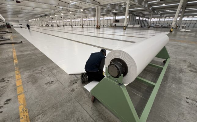 Wielka nadmuchiwana kopuła magazynu energii CO2 firmy Energy Dome na tle terenu przemysłowego.